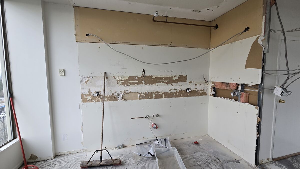 Condo kitchen after demolition — exposed walls and plumbing ready for new cabinetry installation