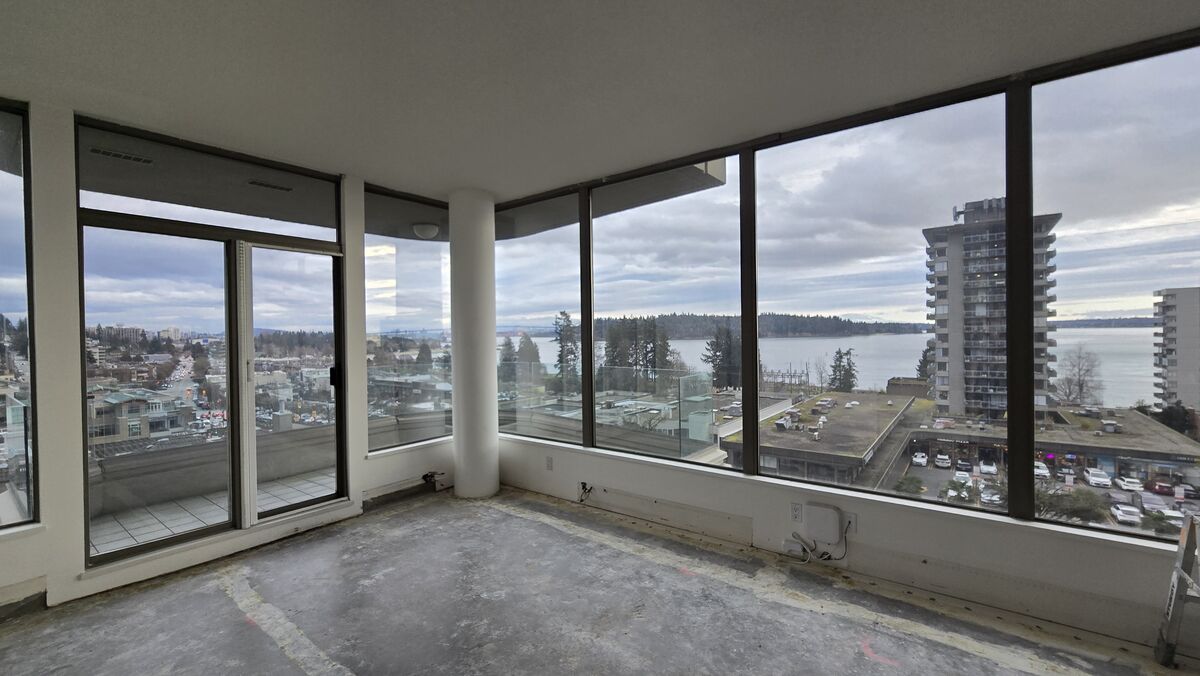 Condo living room after demolition — clean concrete subfloor with panoramic ocean and city views ready for new finishes