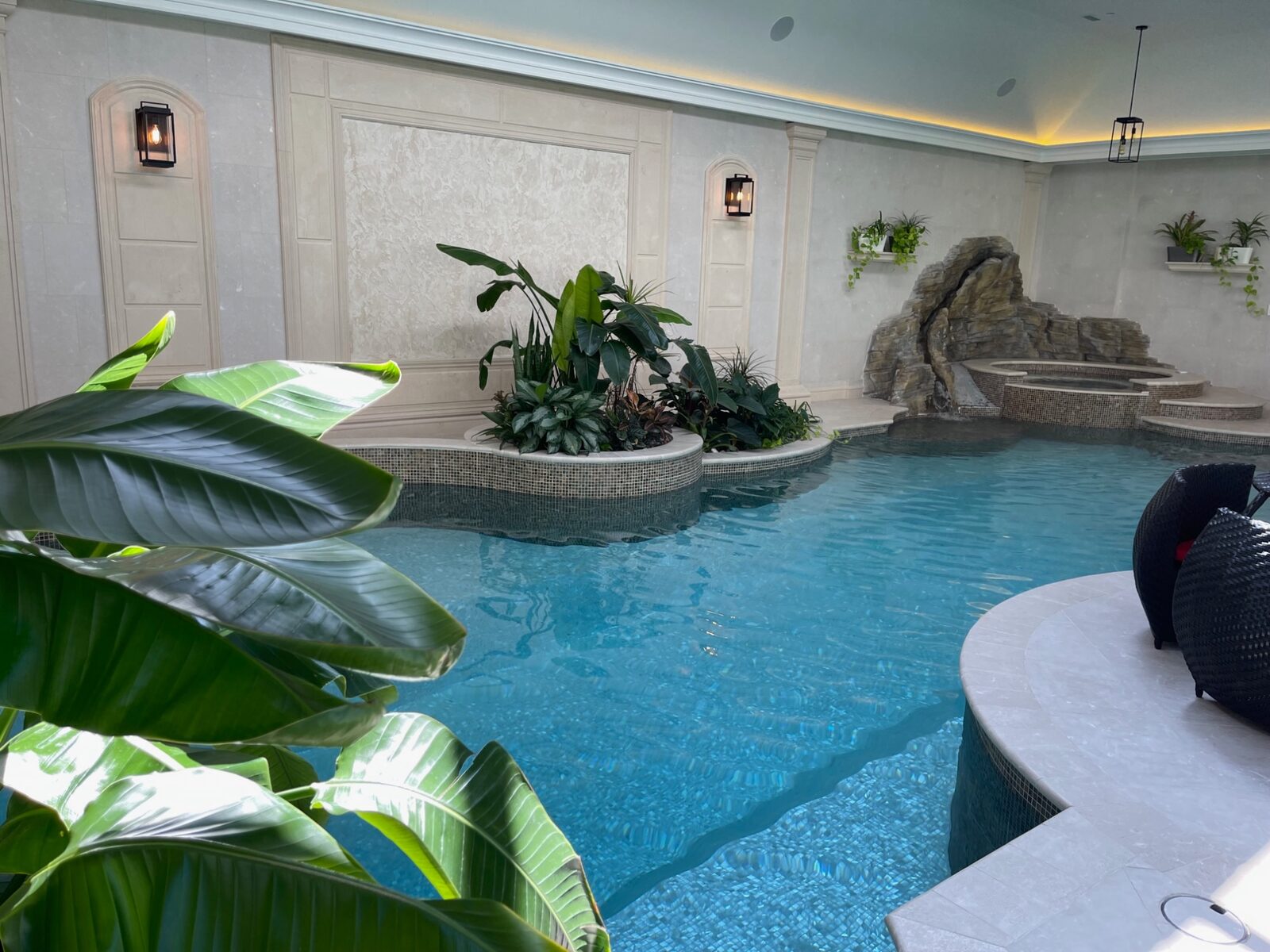 Indoor pool with rock waterfall and tropical landscaping