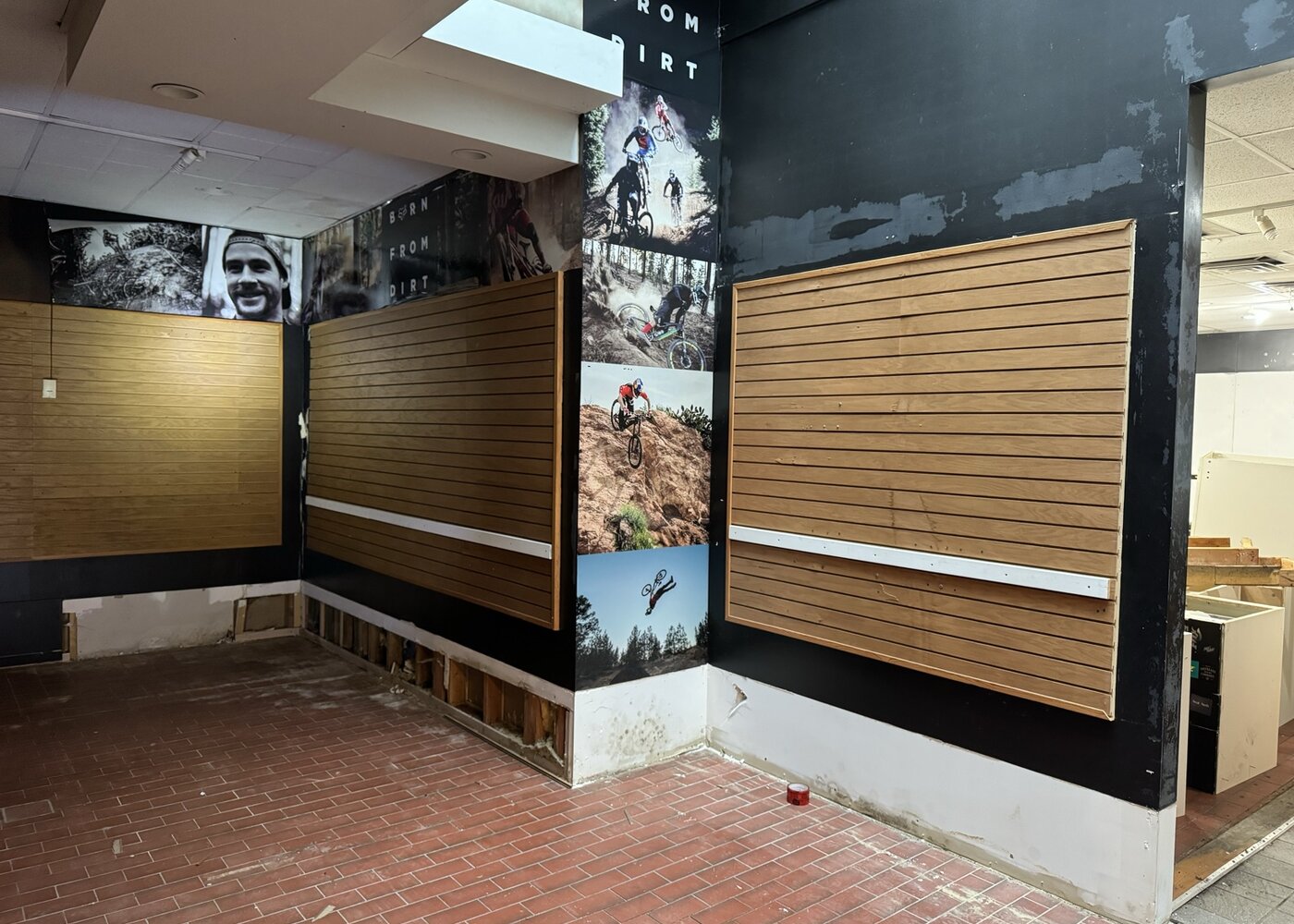 Retail wall displays with slatwall panels and damaged baseboards below requiring restoration