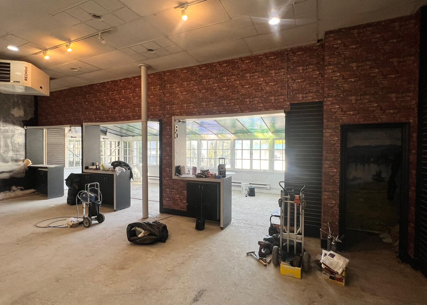 Exposed brick wall with new cabinetry, conservatory windows, and Reznor heater during retail space reconstruction