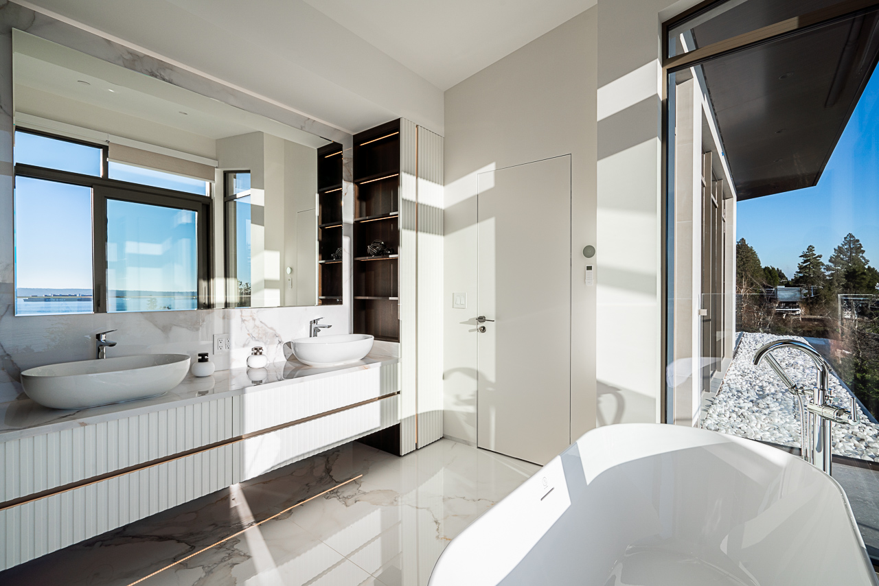 Master ensuite bathroom with dual vessel sinks calacatta marble vanity and freestanding soaker tub with ocean view West Vancouver