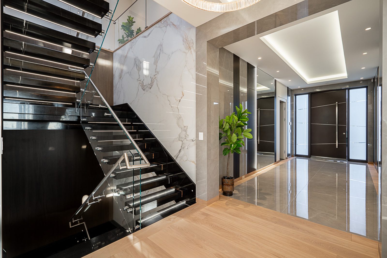 Cantilevered floating staircase with glass railing black marble treads and calacatta accent wall The Butterfly