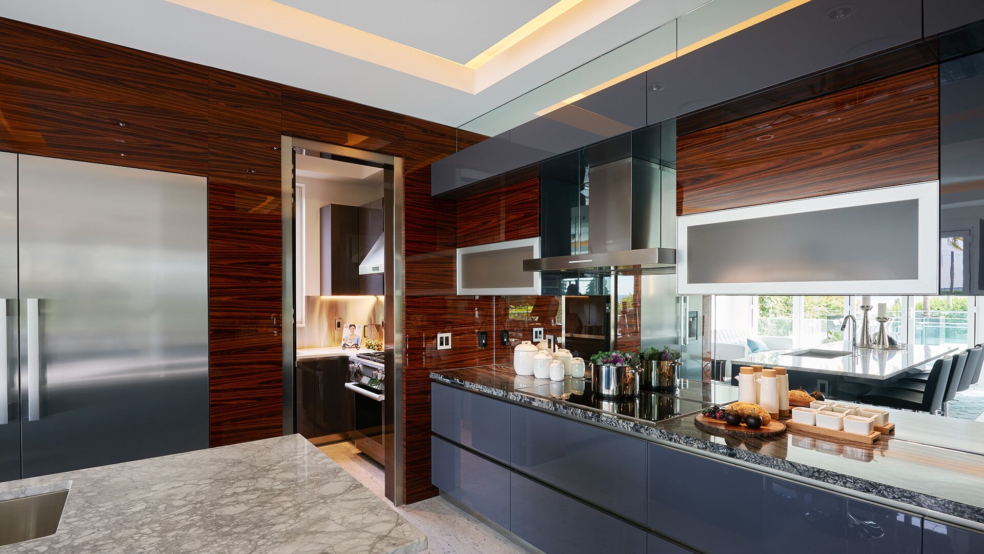 Kitchen detail showing mirror backsplash zebrawood wok kitchen door stainless steel fridge columns and navy cabinetry at California Dreams designed and installed by Eurohouse Construction