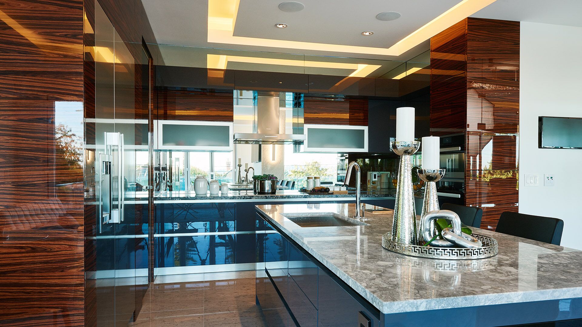 Kitchen angle showing mirror backsplash reflecting outdoor terrace zebrawood panels and granite island at California Dreams designed and installed by Eurohouse Construction