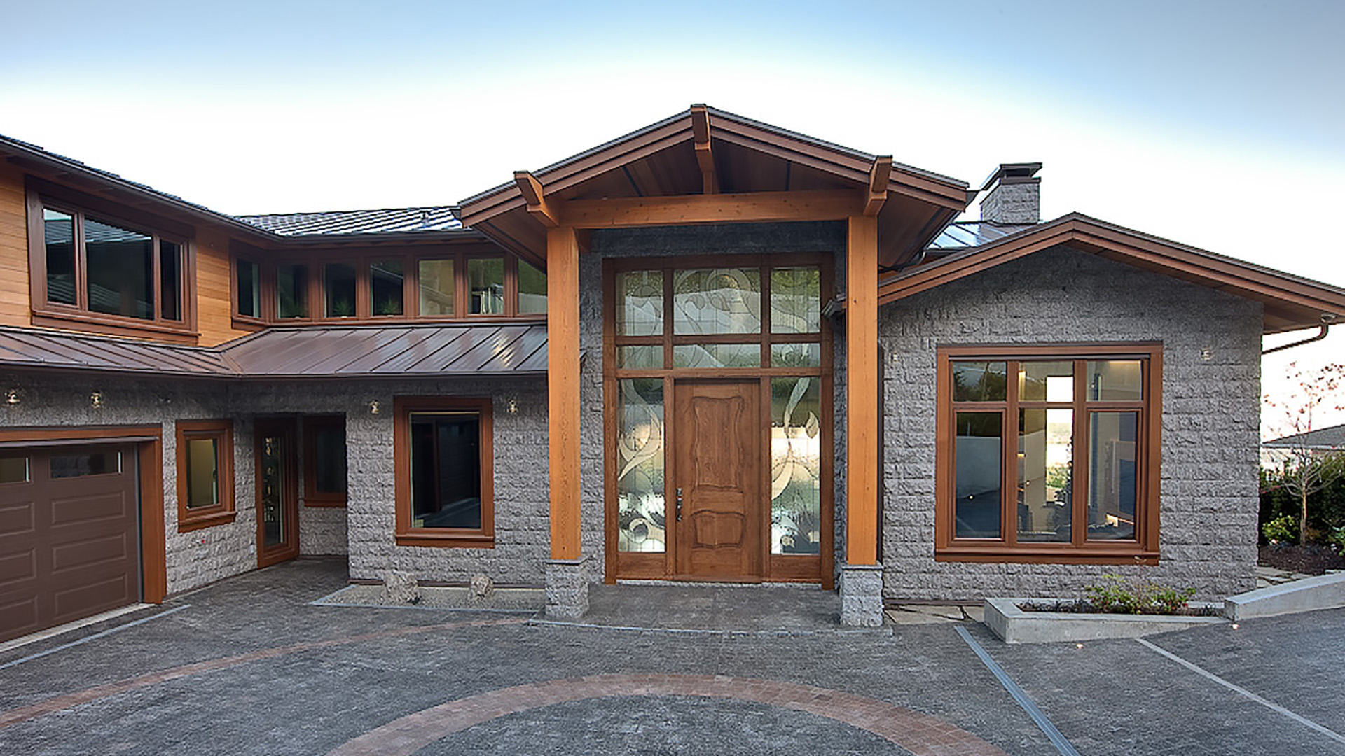 Grand front entrance of Millstream British Properties with natural granite facade timber columns decorative art glass door and copper metal roofing West Vancouver