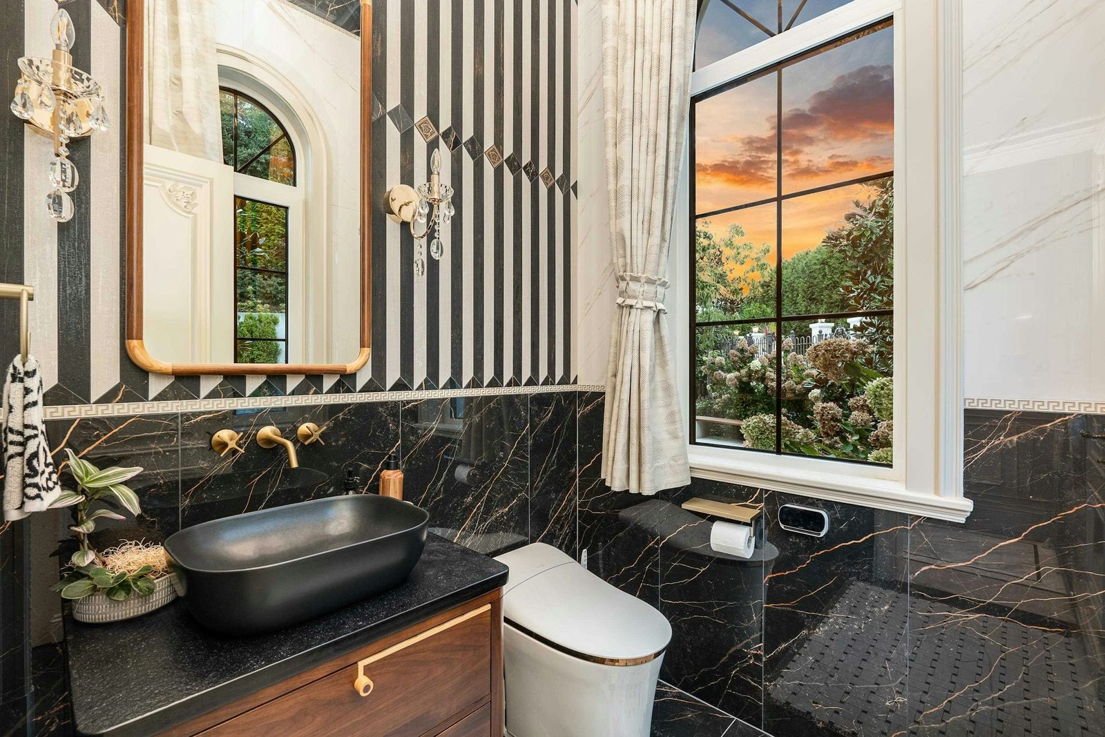 Powder room with black marble walls and gold fixtures in luxury West Vancouver home