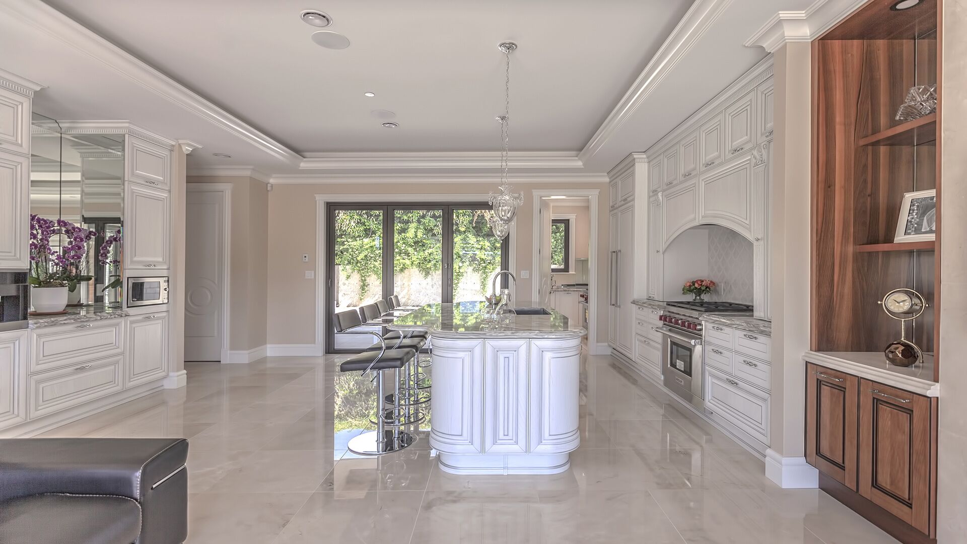 Wide view of classical Italian kitchen with solid wood cabinets, professional range, walnut display shelving, and polished marble floors designed and installed by Eurohouse Construction West Vancouver