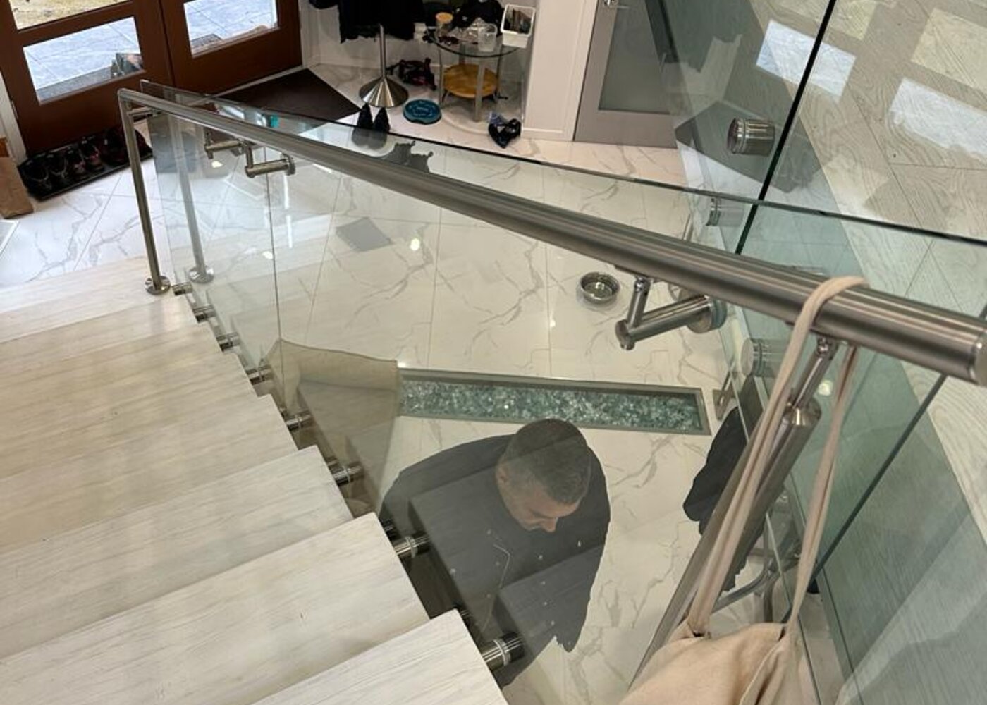 Overview of open staircase with glass railings and marble entry floor in luxury North Vancouver residence before water damage