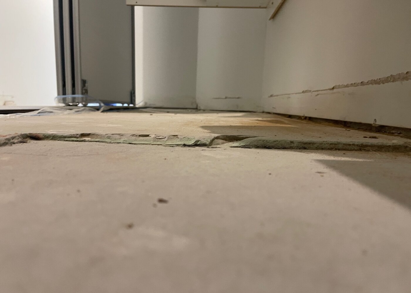 Uneven subfloor transition between rooms with visible height differences and gaps requiring self-levelling compound treatment