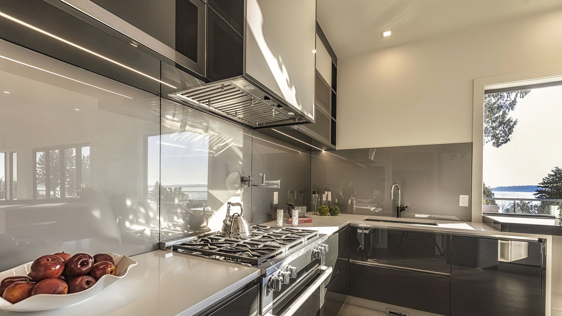 Close-up of Italian gloss kitchen cabinetry with integrated range hood, professional gas cooktop, and LED under-cabinet lighting by Eurohouse Construction