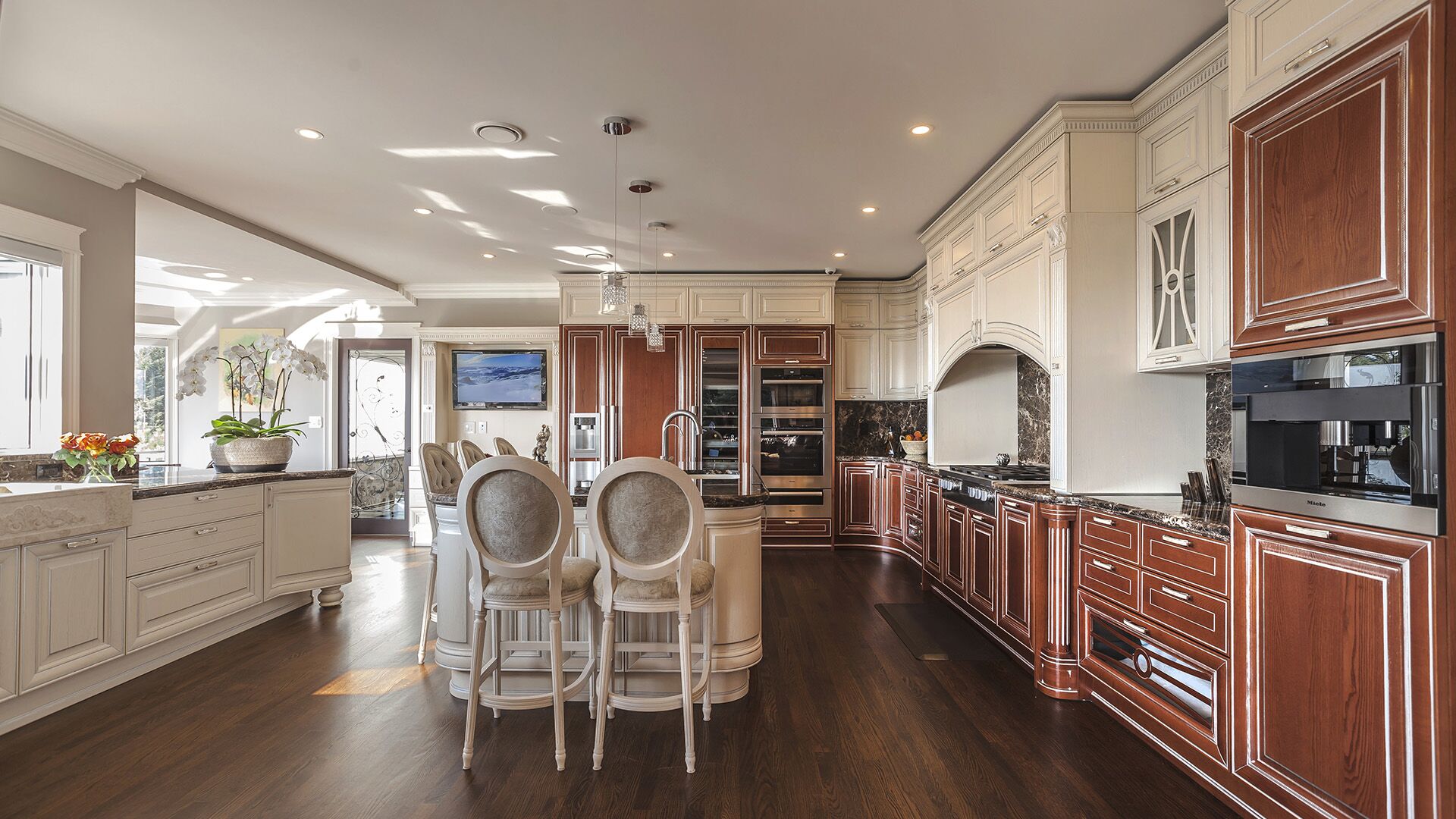Kitchen from living area showing open plan flow arched front door crystal pendants cherry built-in media cabinet and Miele appliance wall at Rockridge Classic built by Eurohouse Construction