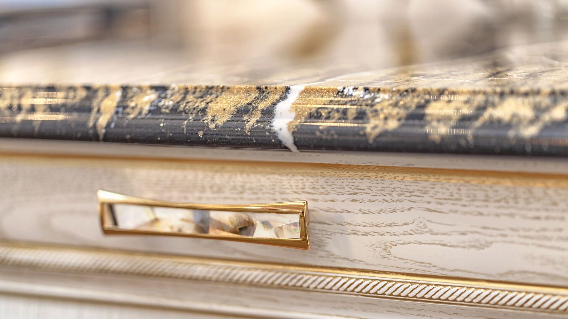 Macro detail of mother-of-pearl inlay hardware on Italian solid wood cabinetry with gold leaf edge and dark veined granite by Eurohouse Construction