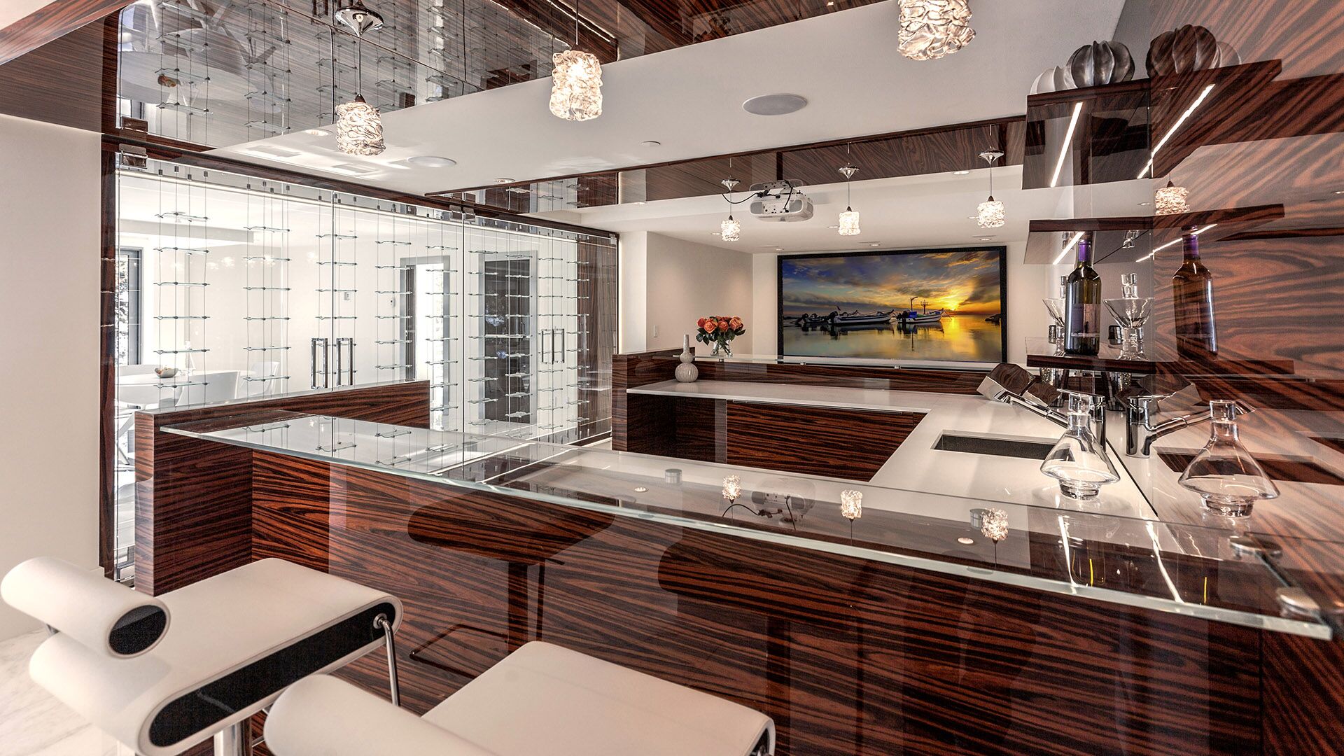 Luxury entertainment bar with high-gloss zebrawood millwork glass-enclosed wine cellar crystal pendant lights and projector screen at The Riva Club designed and installed by Eurohouse Construction Vancouver