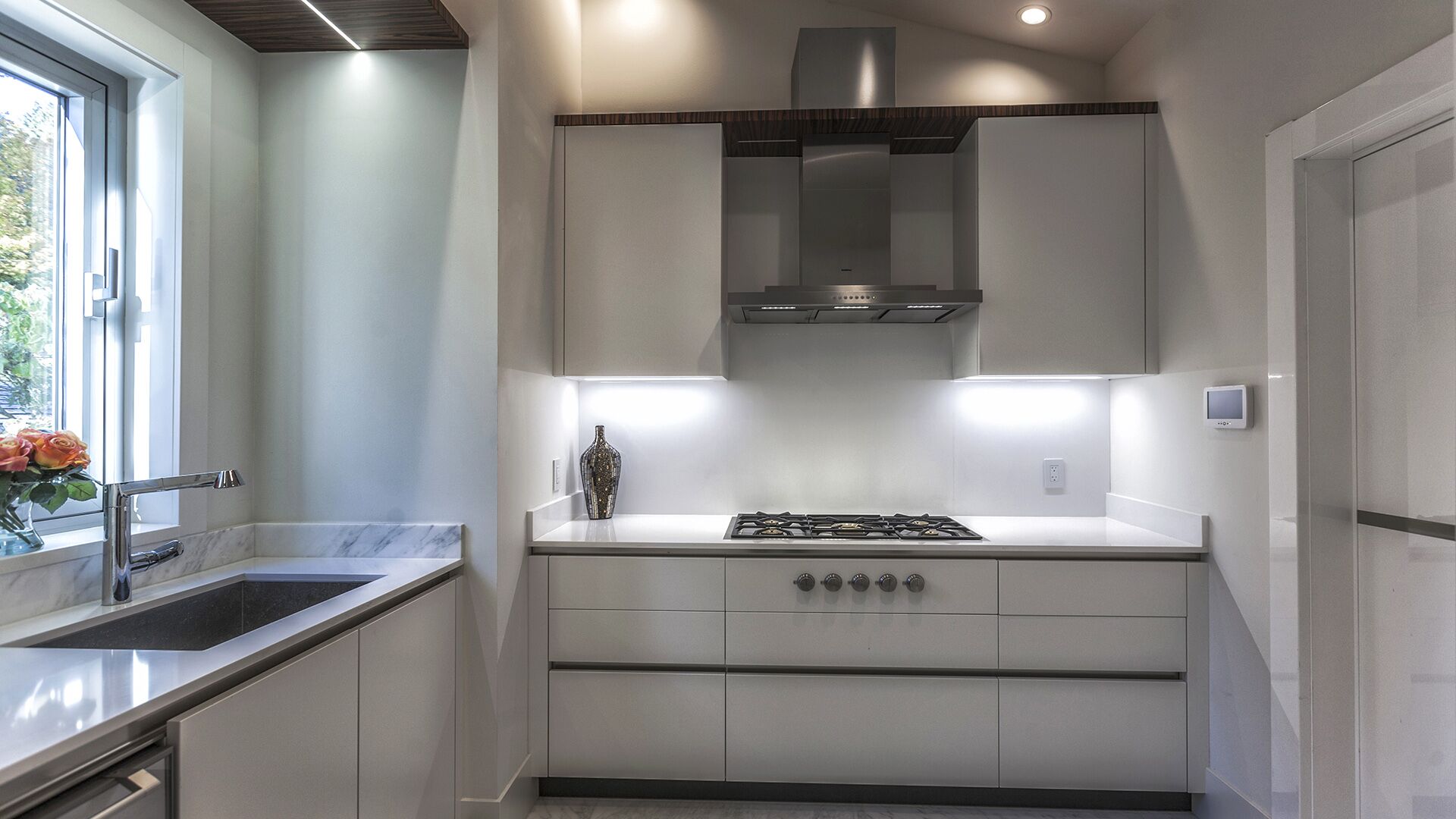 Dedicated wok kitchen with white cabinetry gas cooktop under-cabinet LED lighting and zebrawood ceiling trim at The Riva Club designed and installed by Eurohouse Construction