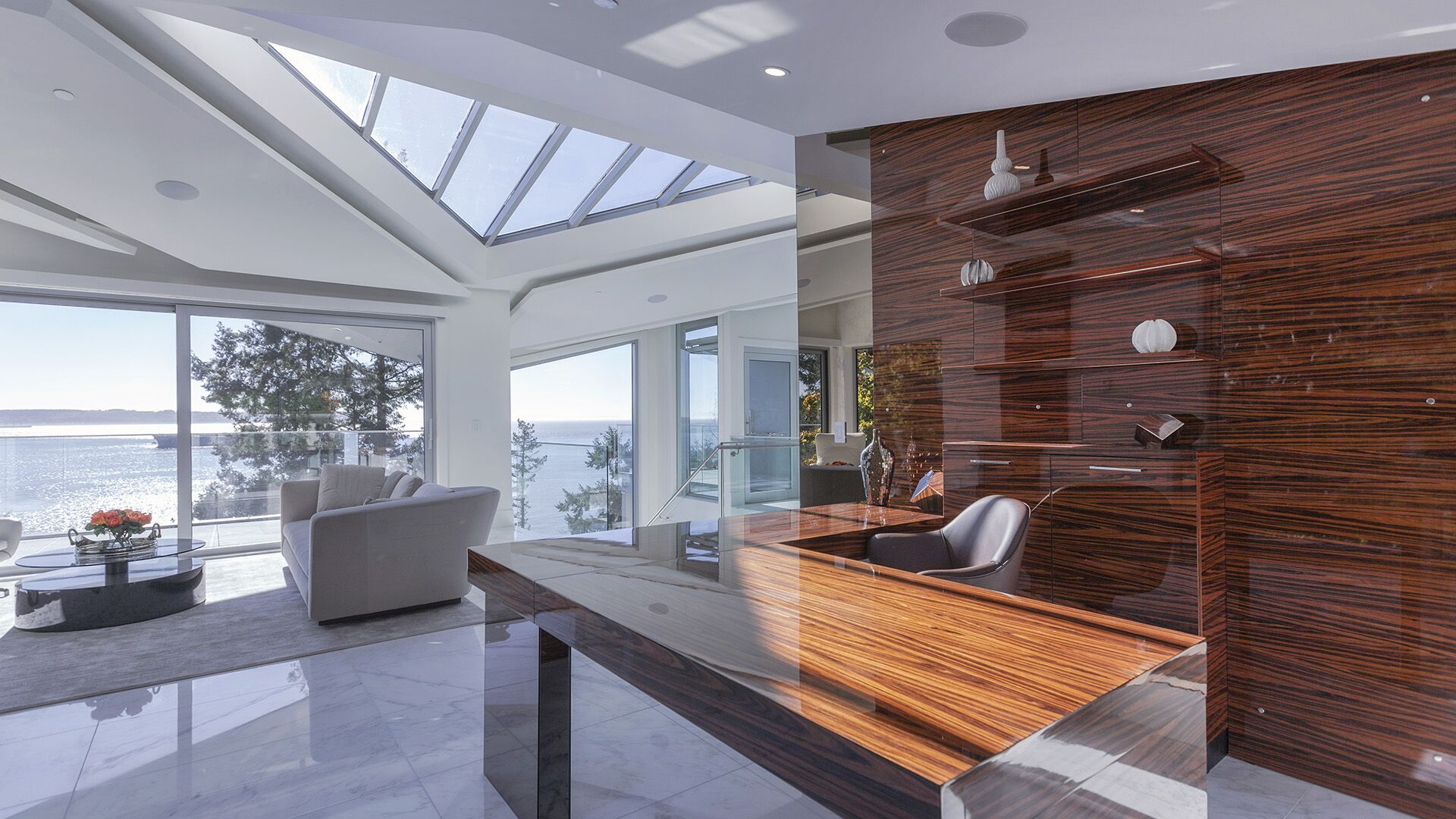 Luxury study with zebrawood floating desk and wall panel vaulted skylights ocean views and glass stairwell railing at The Riva Club designed and installed by Eurohouse Construction