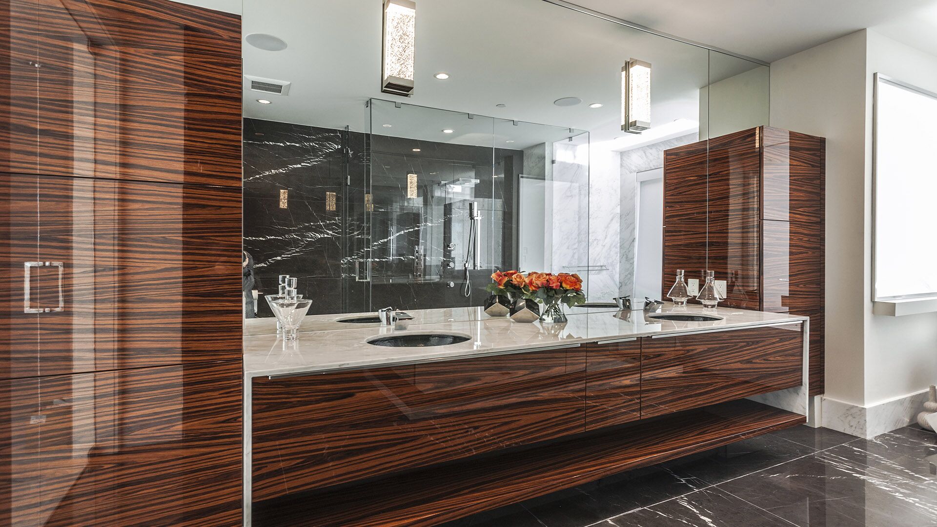 Luxury master bathroom with zebrawood floating vanity Nero Marquina black marble floor and shower white Calacatta countertop and crystal sconces at The Riva Club designed and installed by Eurohouse Construction