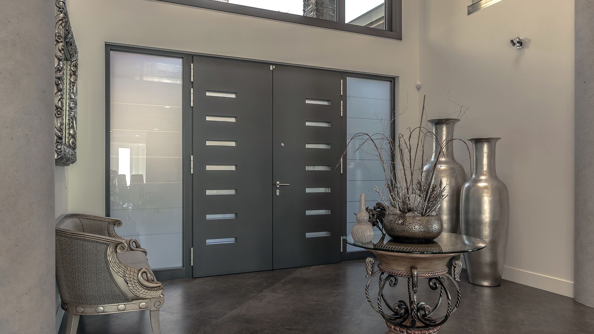 Italian entry door detail with frosted glass sidelights large-format porcelain tile concrete walls and silver vases at The Zen on Bramwell renovated by Eurohouse Construction British Properties