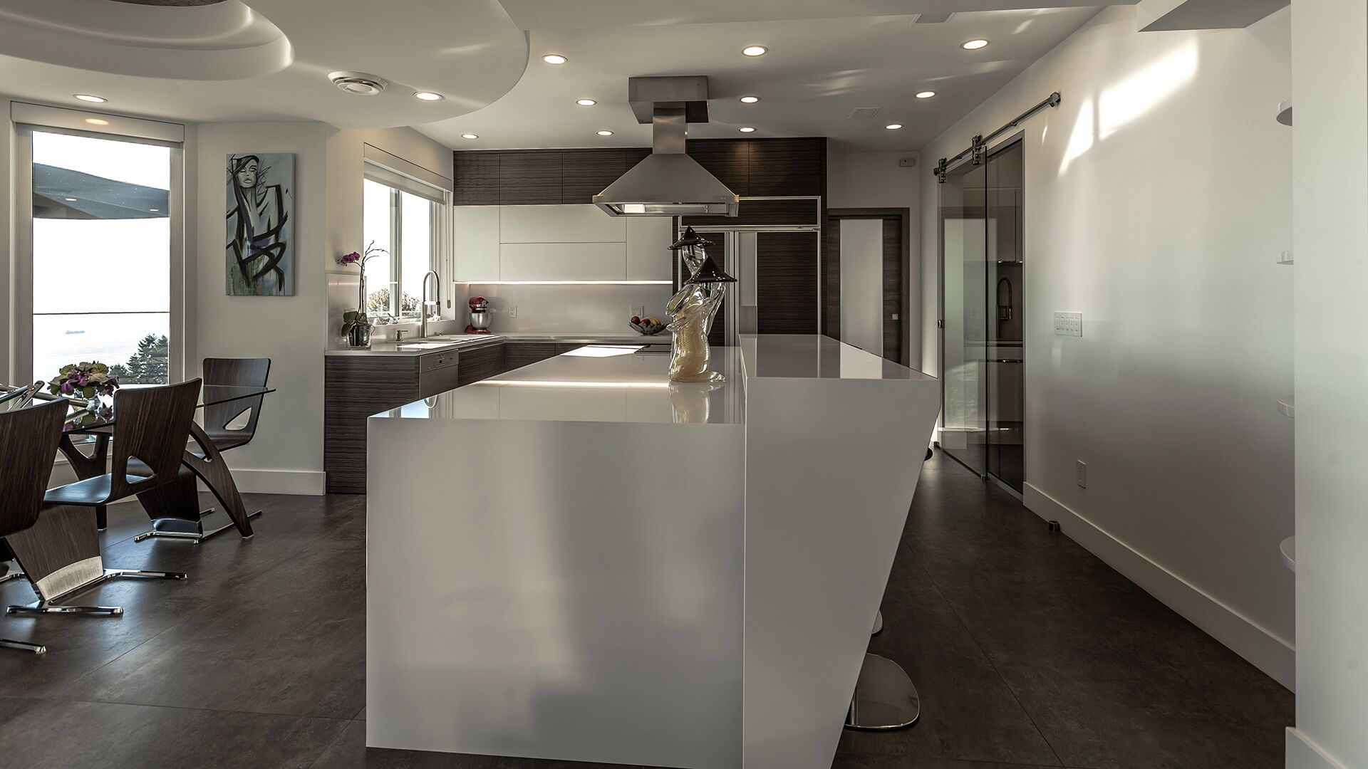 Italian kitchen with dark veneer handleless cabinetry white quartz waterfall island Wolf cooktop sculptured ceiling barn door and large-format porcelain tile at The Zen on Bramwell renovated by Eurohouse Construction