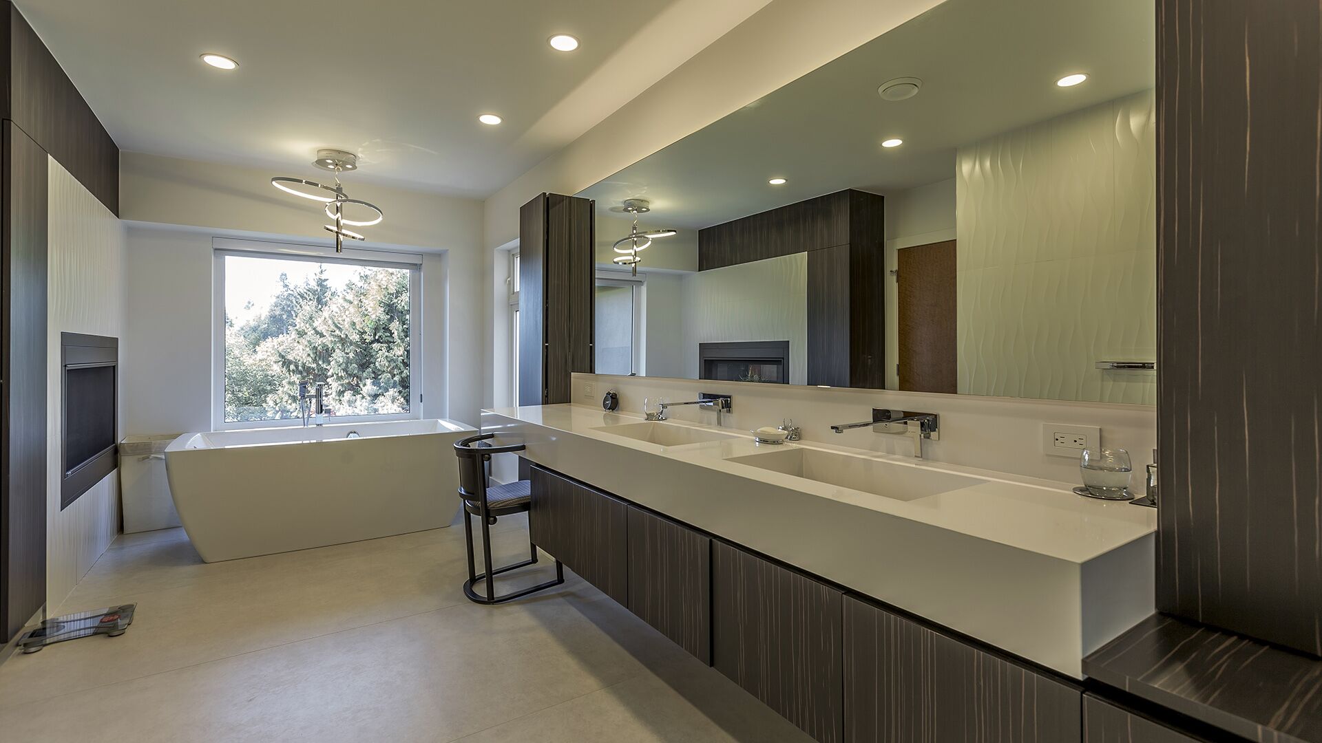 Master ensuite with freestanding soaking tub garden views Italian dark veneer floating vanity white quartz countertop wave-texture wall tile and modern ring pendant at The Zen on Bramwell renovated by Eurohouse Construction
