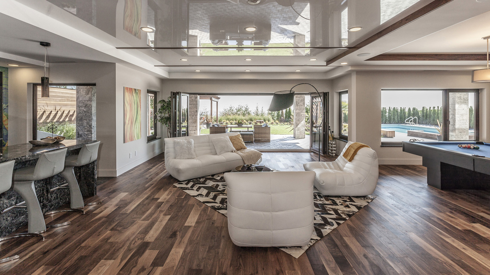 Lower level recreation room with stretch ceiling marble bar pool table folding eclipse doors to covered patio and pool views West Coast Contemporary British Properties West Vancouver
