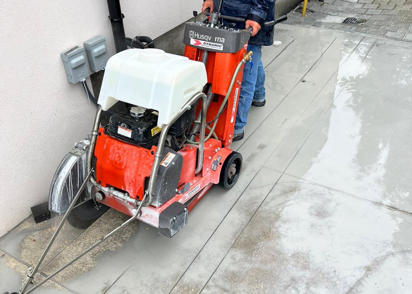 Husqvarna concrete saw cutting perimeter slab along foundation wall for waterproofing access