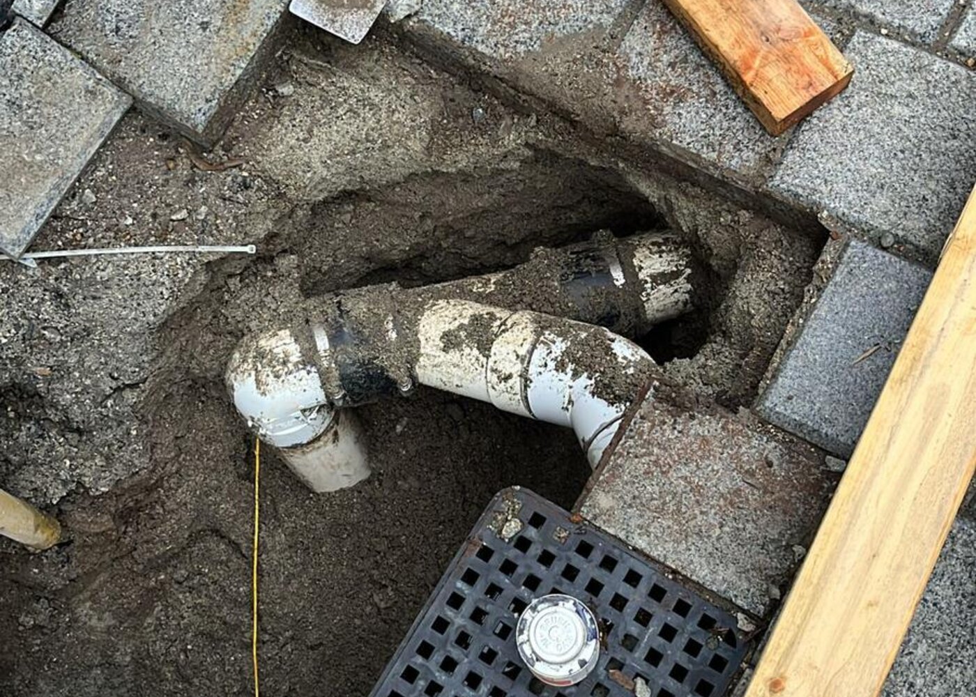 New drainage connection installed at paver level with catch basin and PVC piping during foundation repair