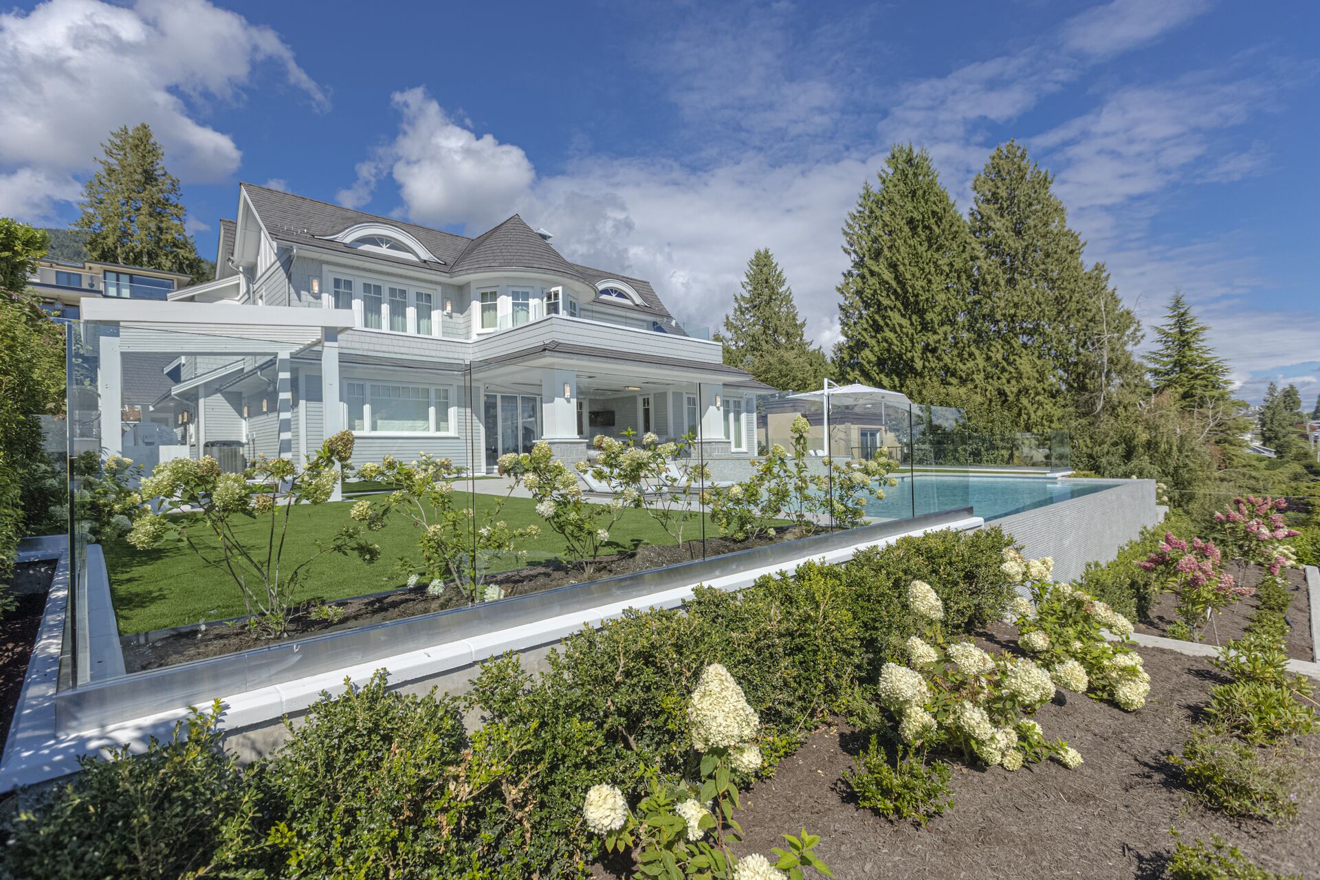 Landscaped gardens with glass pool railing and hydrangeas at luxury West Vancouver home by Eurohouse