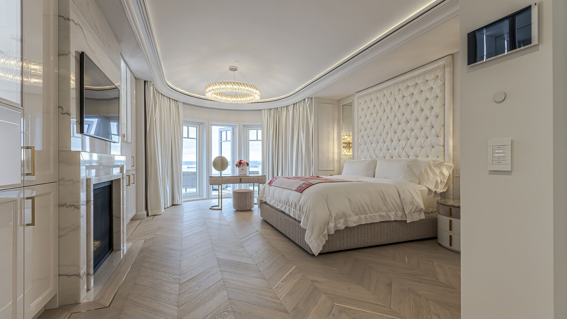 Master suite with tufted headboard herringbone floors marble fireplace curved bay window and ocean views West Vancouver luxury home Eurohouse Construction